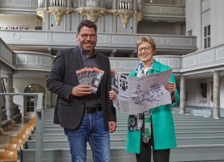 Regionalbischöfin Gisela Bornowski und ihr Referent, Kirchenrat Dr. Gerhard Gronauer, präsentieren das Faltblatt in der barocken St. Gumbertuskirche in Ansbach